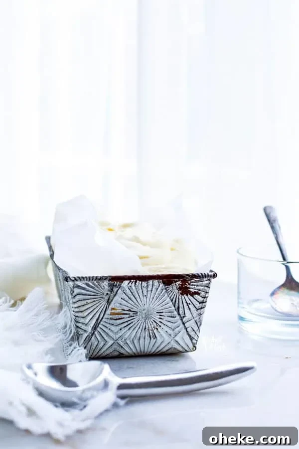 Homemade Vanilla Ice Cream in a silver loaf pan lined with parchment paper ready to be served
