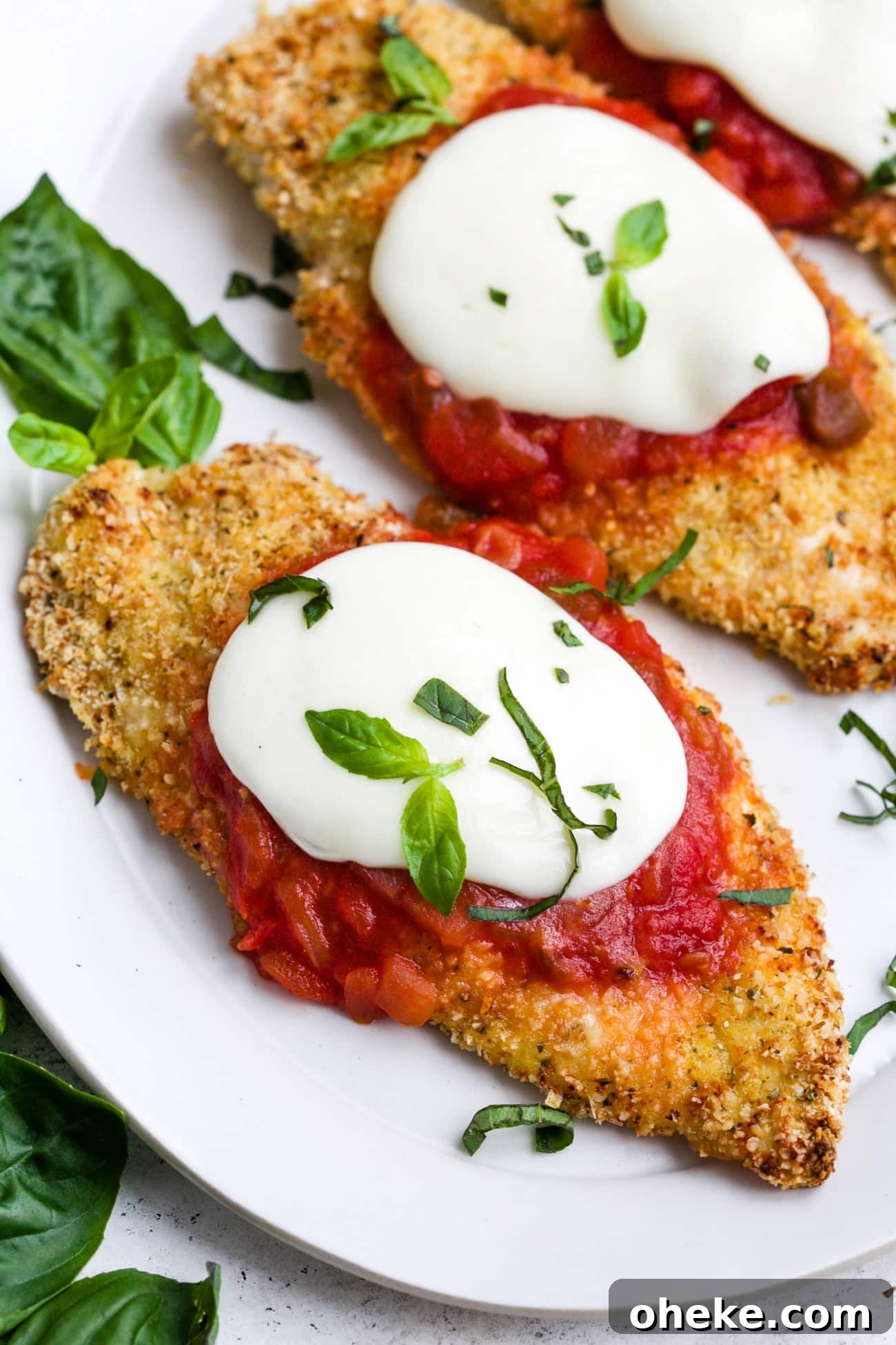 Baked chicken parmesan on a white serving plate.