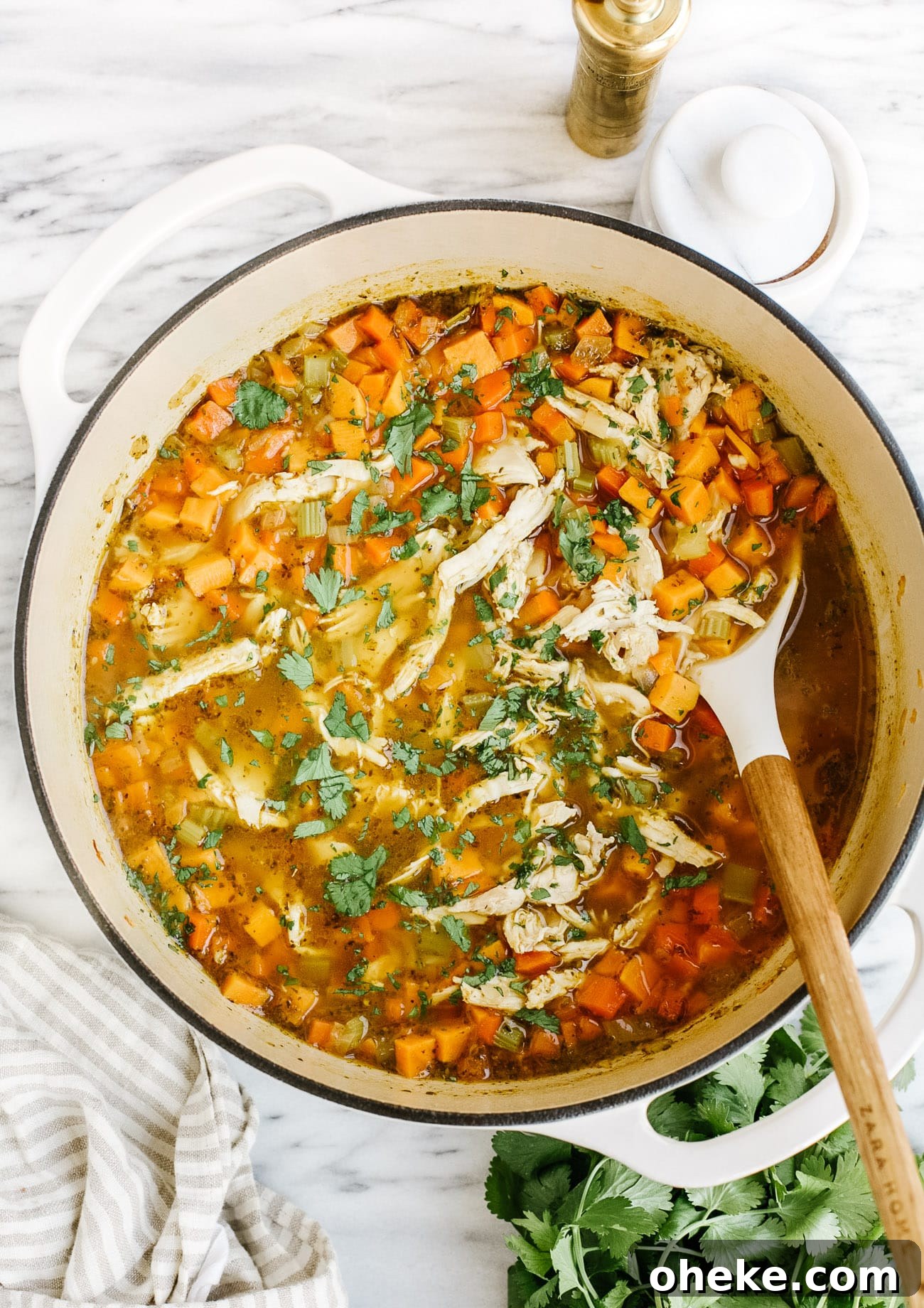 overhead view of sweet potato chicken soup in a white Dutch oven pot