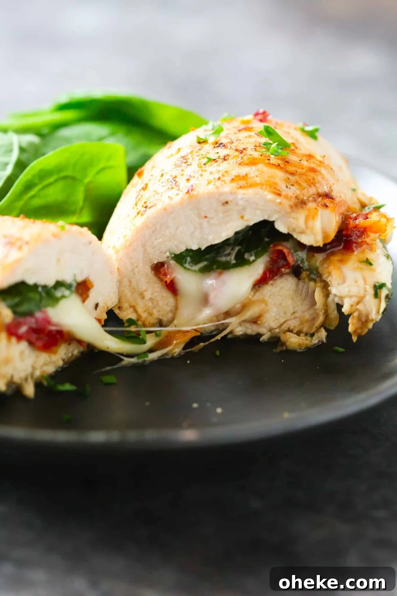 close up of a Sun Dried Tomato, Spinach and Cheese Stuffed Chicken on a black plate