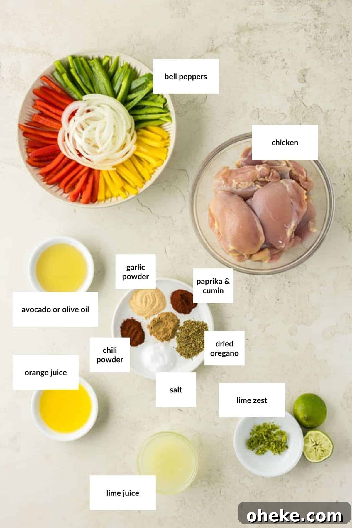 Colorful sliced bell peppers and onions, raw chicken thighs for grilled chicken fajitas, spices, dried oregano, garlic powder, lime juice, orange juice, lime zest, and olive oil arranged on a light surface.
