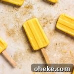 Homemade mango popsicles with wooden popsicle sticks.