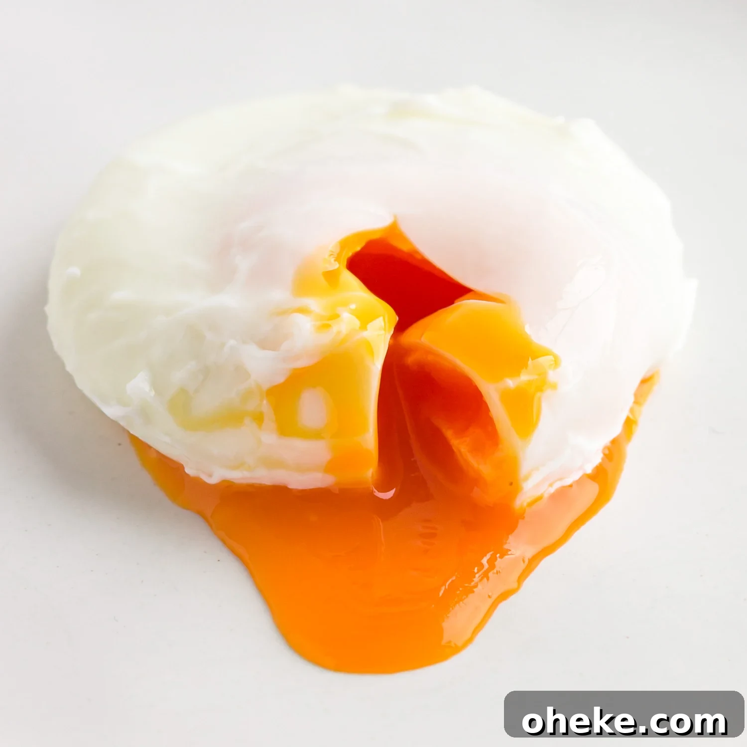 Closeup of a poached egg that has been cut into to release the golden, runny yolk.